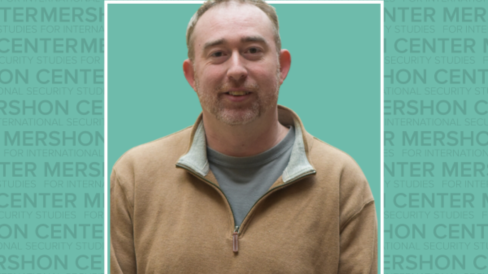 Photo of Brooks Marmon in a tan quarter zip sweater on a teal background that has repeating Mershon Center text.
