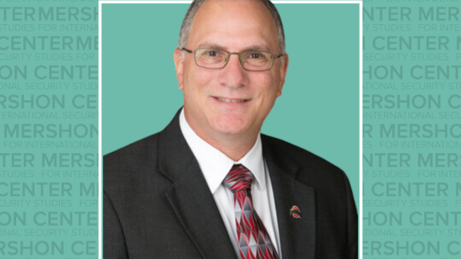 Photo of Peter Mansoor in a suit with a teal background that repeats the word Mershon Center.