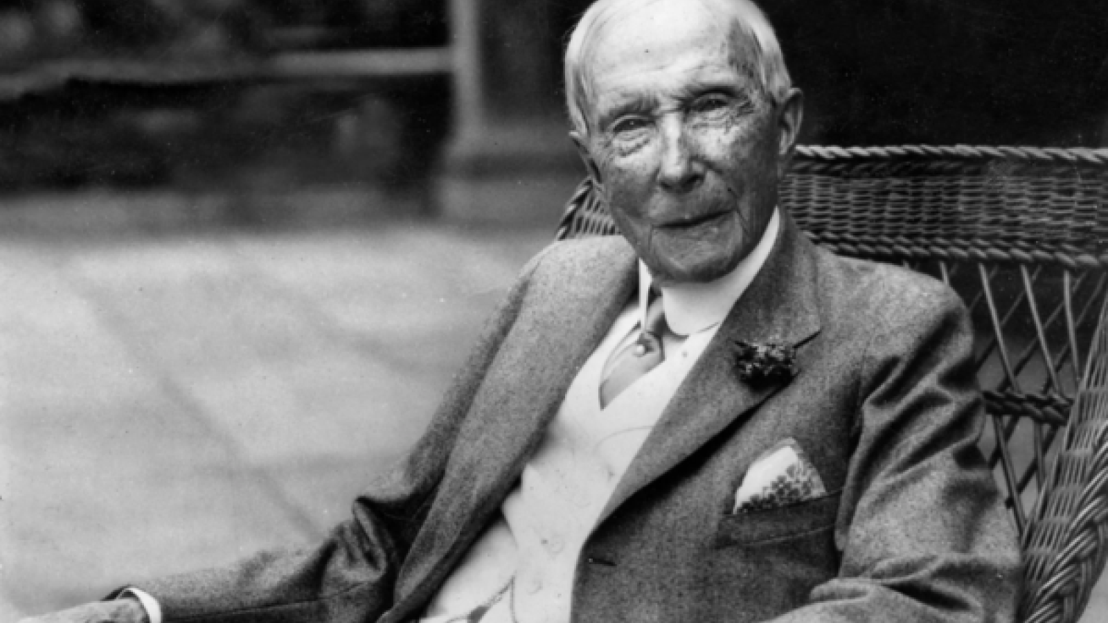 Old man sitting in rattan chair in 3 piece suit