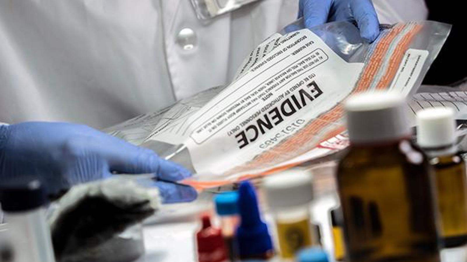 person in lab coat holding evidence bag 