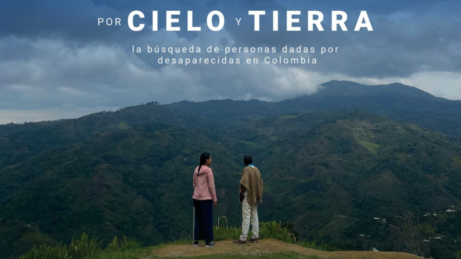 Two people on a hill with mountains in the background
