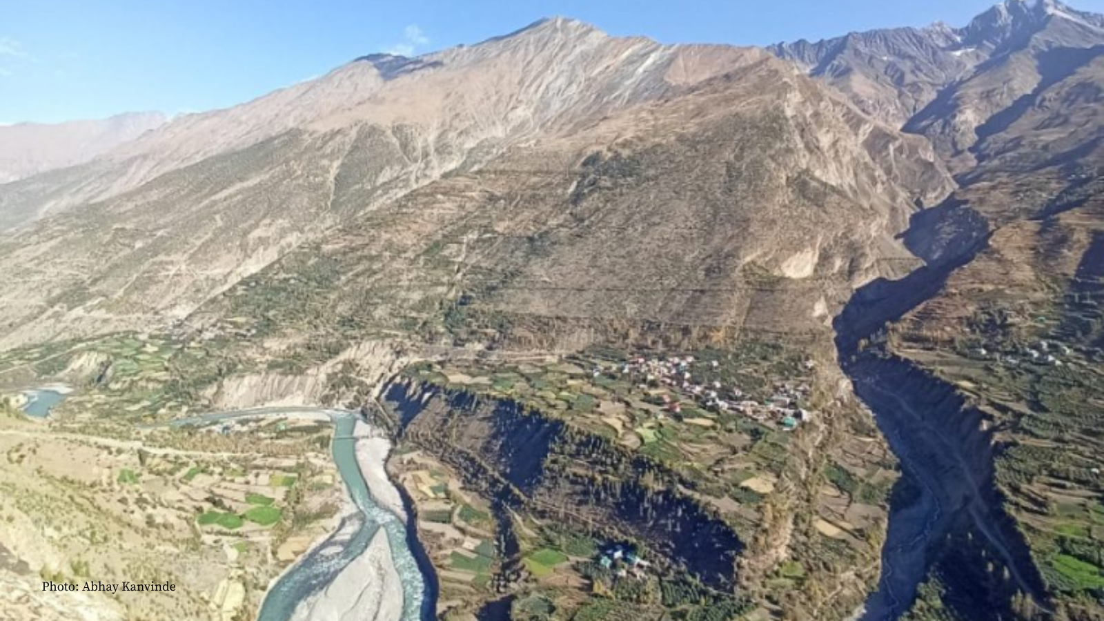 A brownish green mountain with a forked glacial stream at its base
